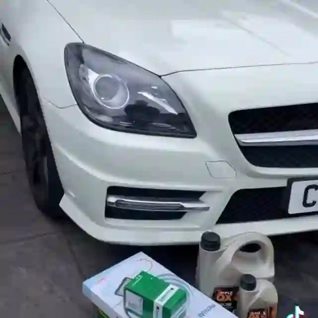 A white Mercedes SLK with fresh oil and service parts laid out ready