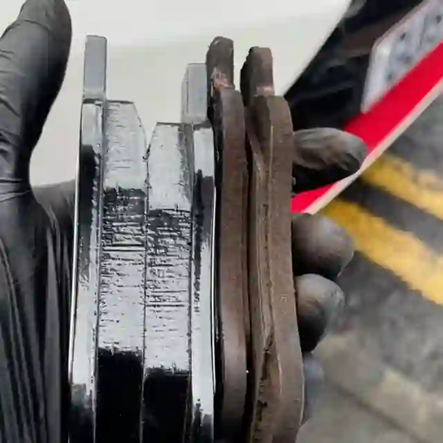 Worn brake pads held up next to fresh ones during a doorstep brake job