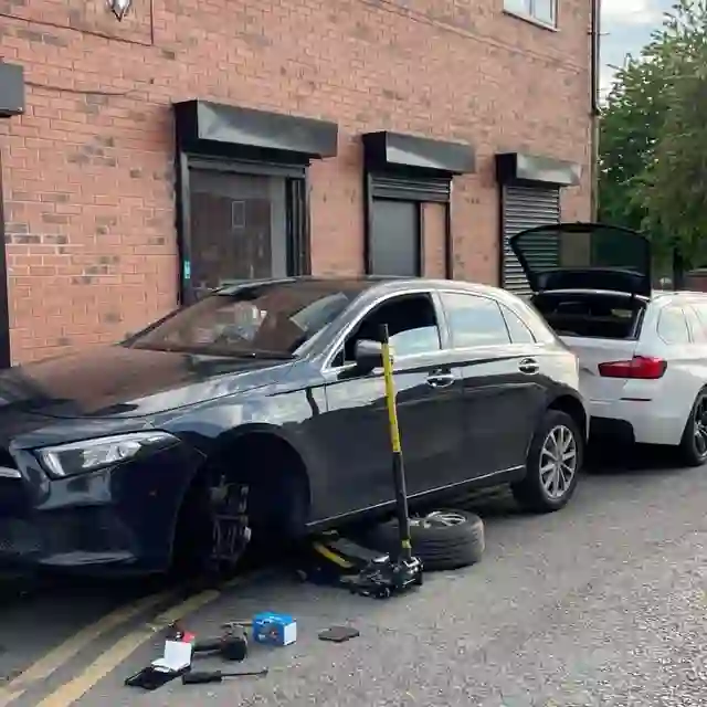 A Mercedes with a wheel removed being worked on kerbside by AutoDr